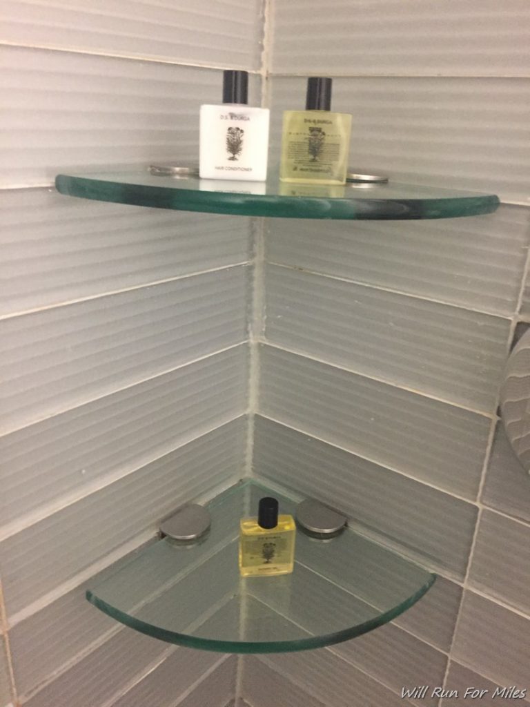 a glass shelf with bottles of nail polish on it