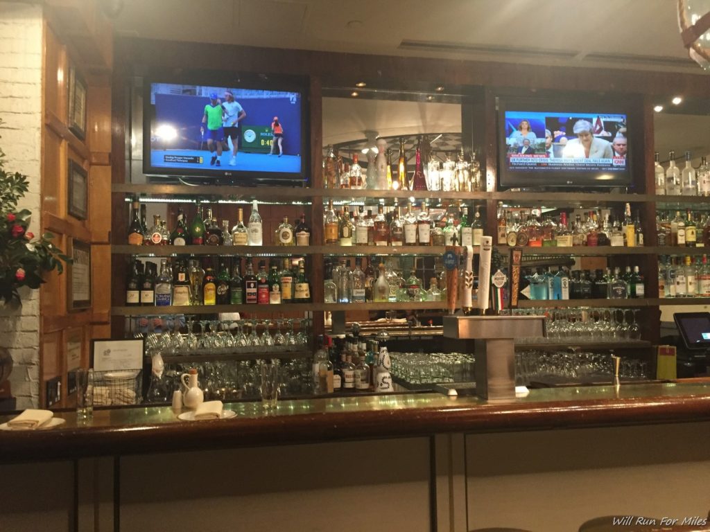 a bar with a shelf full of liquor and televisions