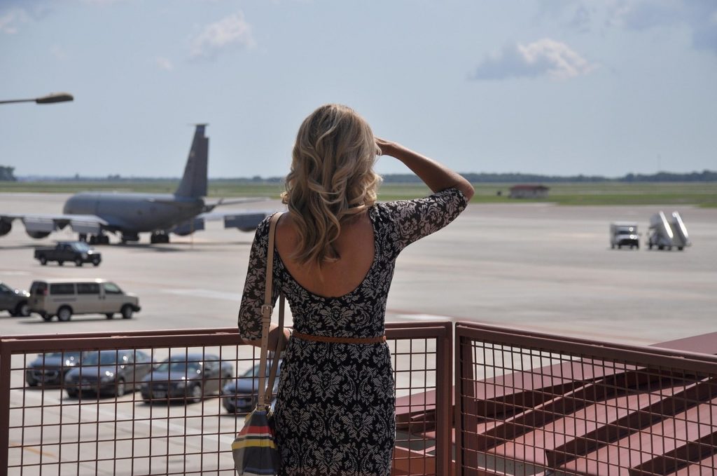 a woman standing on a railing looking at an airplane