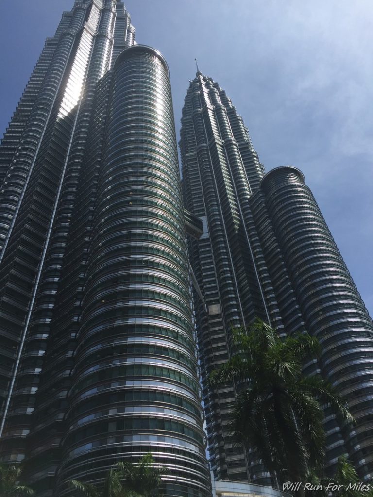 a tall building with many windows with Petronas Towers in the background