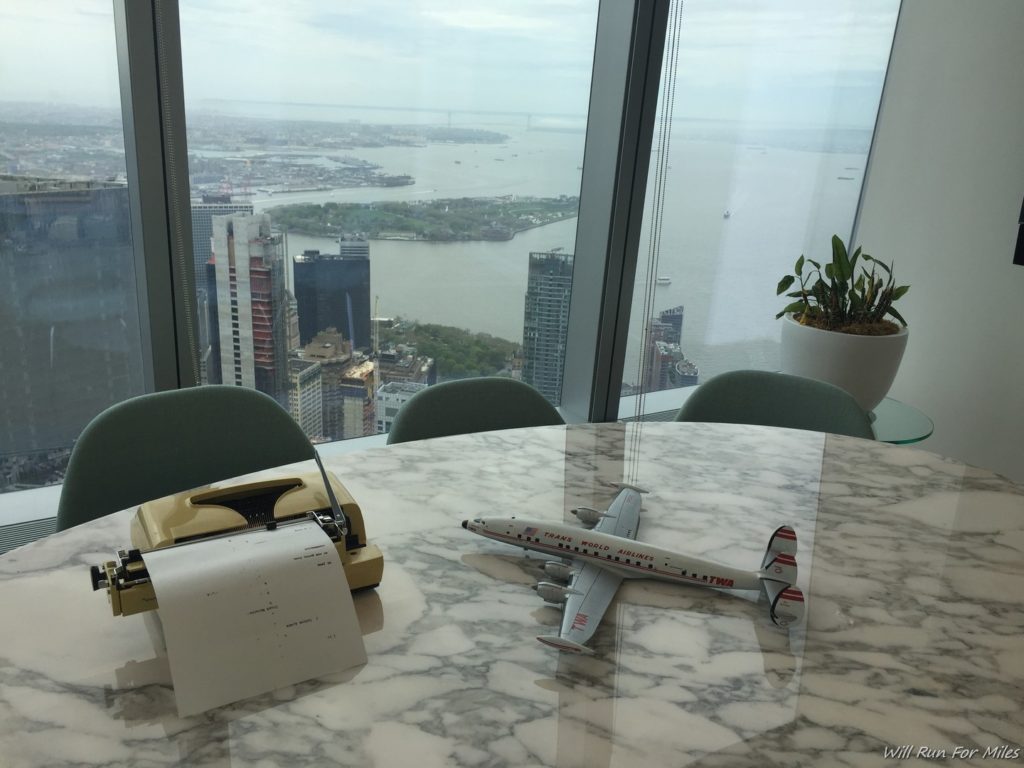 a model airplane on a table with a typewriter and a city view