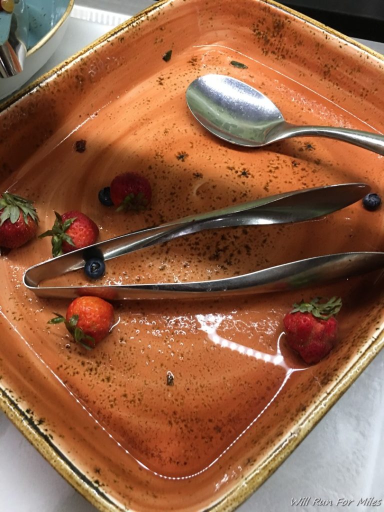a bowl of fruit and tongs