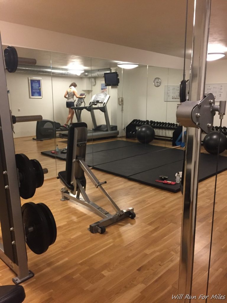 a mirror of a gym with a woman running on treadmills