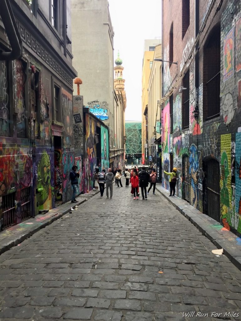 a group of people walking down a narrow street with graffiti