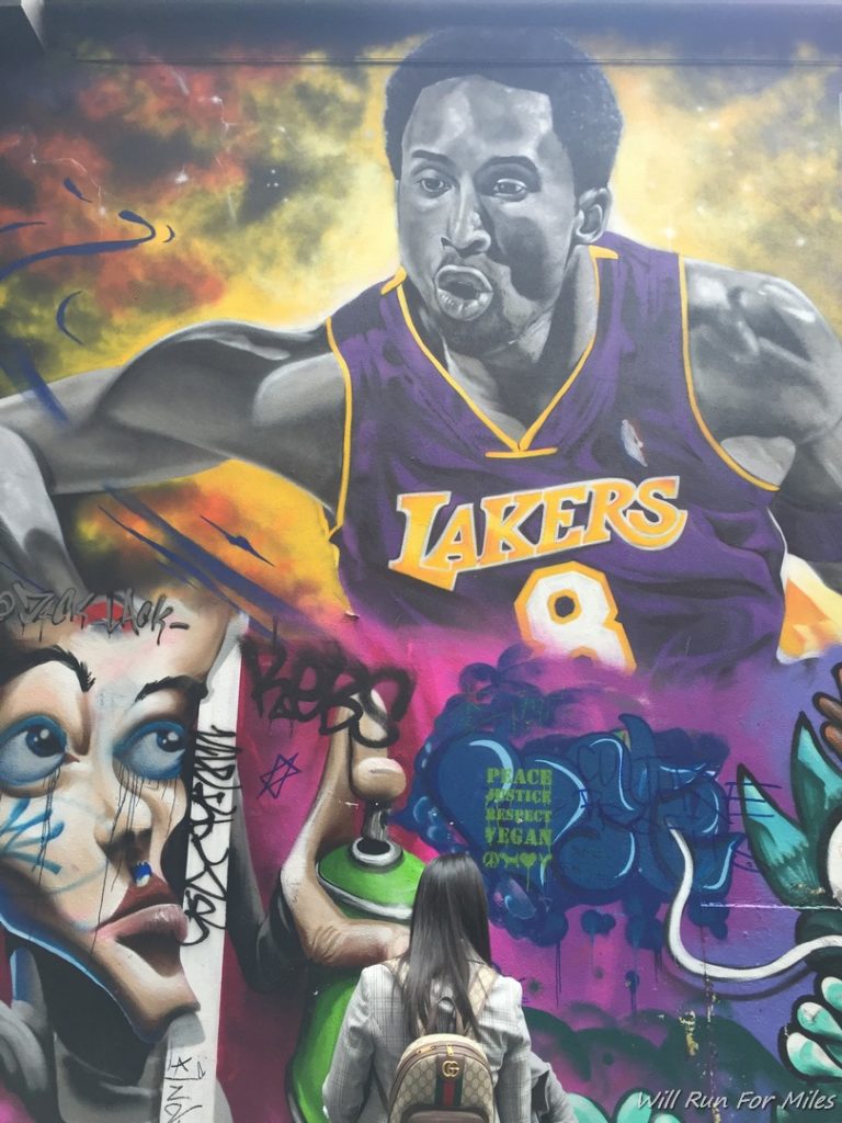 a woman looking at a mural of a basketball player