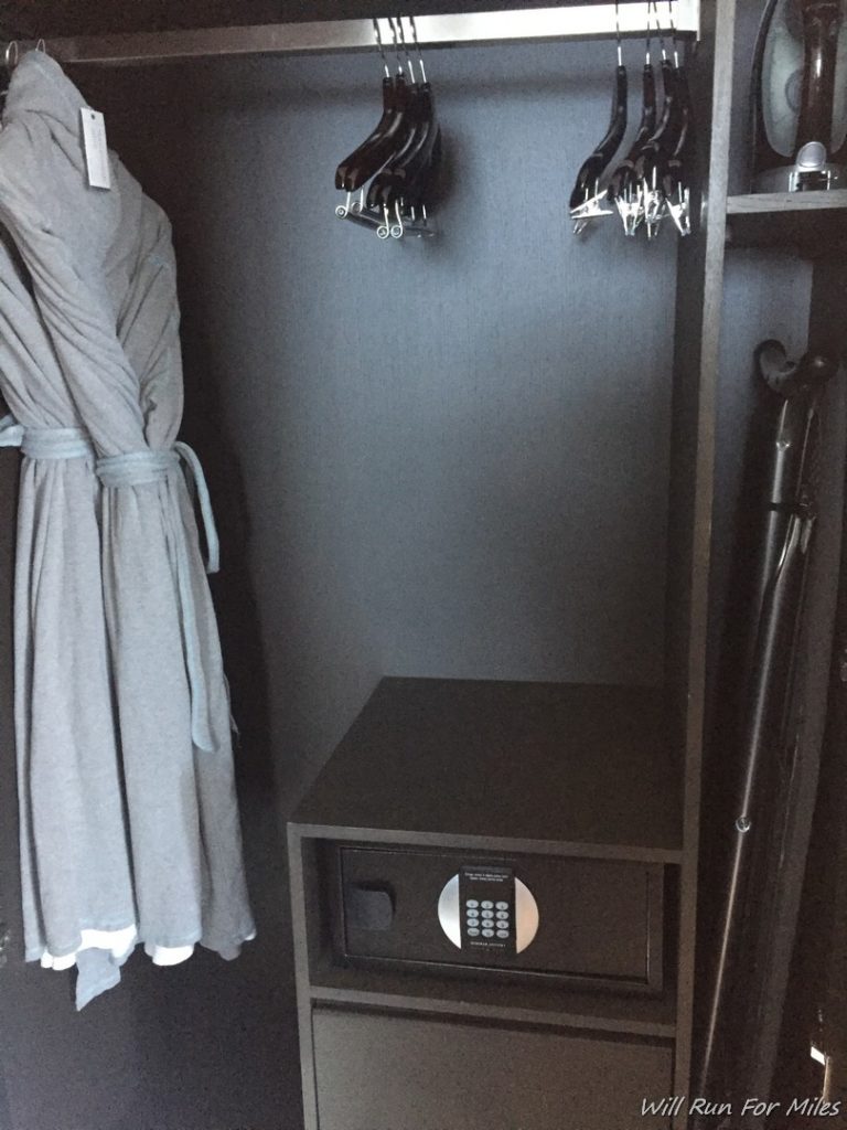 a black closet with a grey robe and a black wall