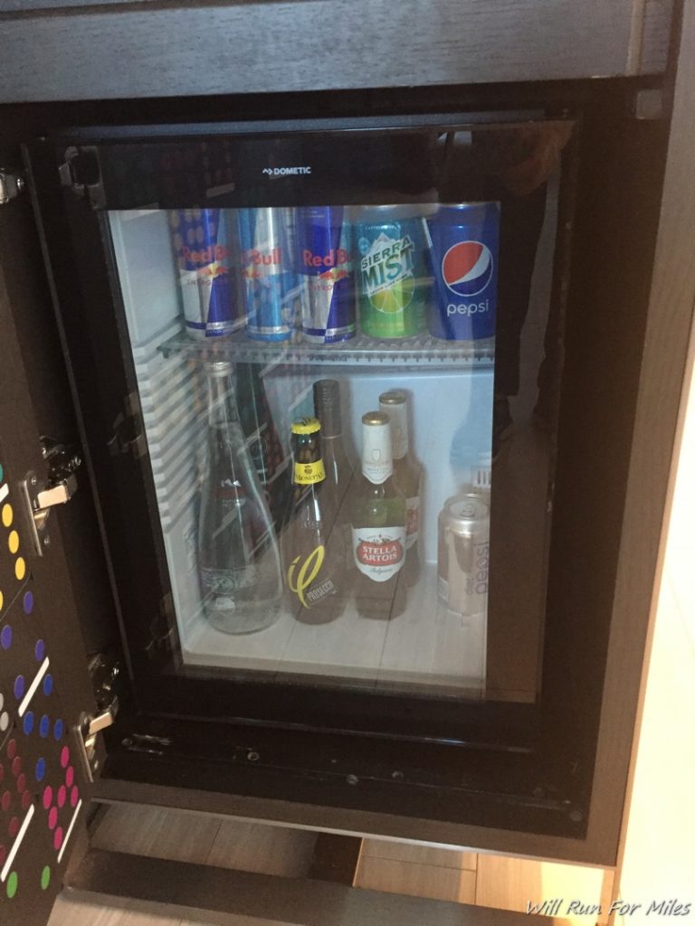 a mini fridge with bottles and cans of soda