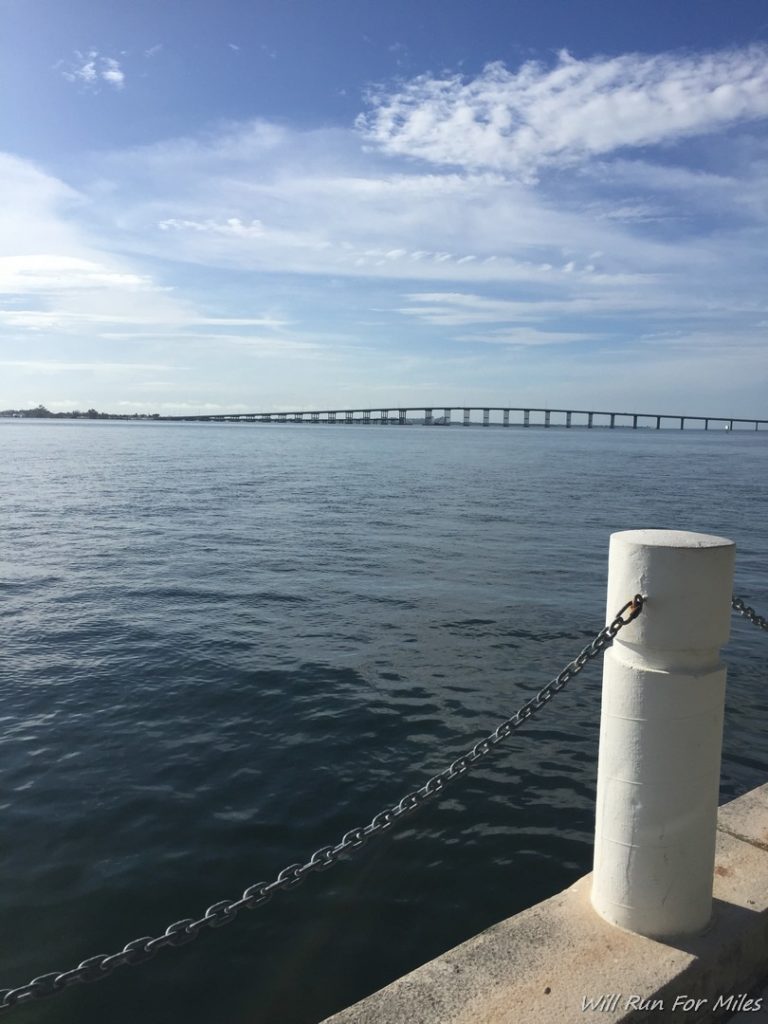 a white pole with a chain around it and a bridge in the background