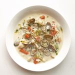 a bowl of soup with clams and vegetables