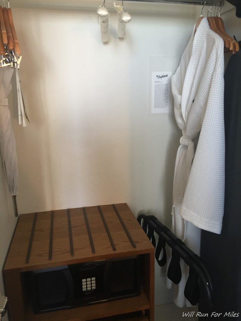 a white robe on a swinger next to a wooden shelf