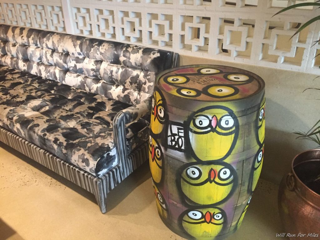 a barrel with yellow birds painted on it next to a couch