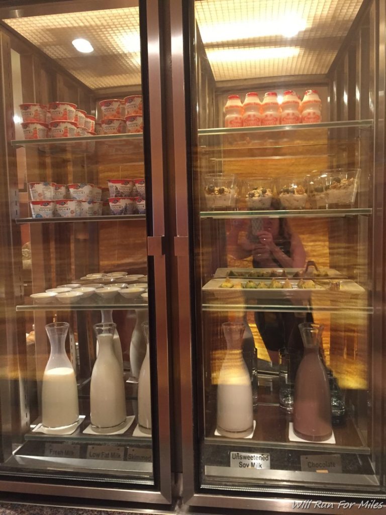 a woman taking a picture of a glass case of food