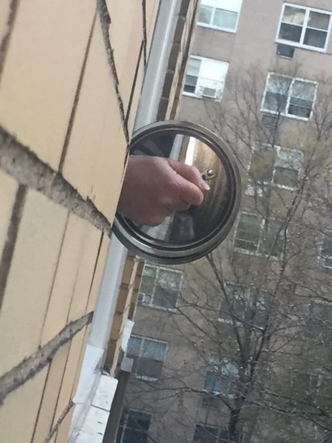 a hand holding a mirror through a window