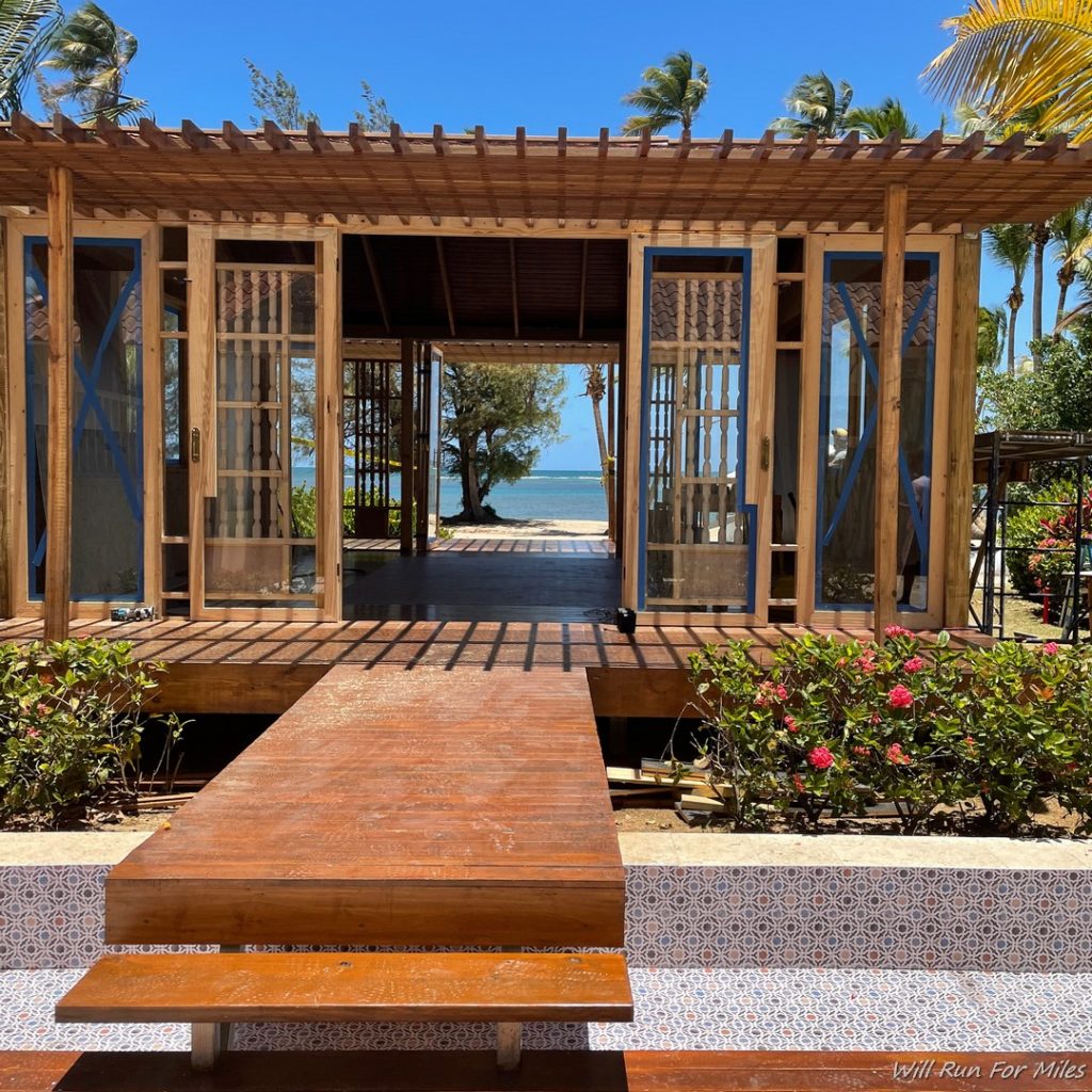 a wooden structure with a table and benches on a beach