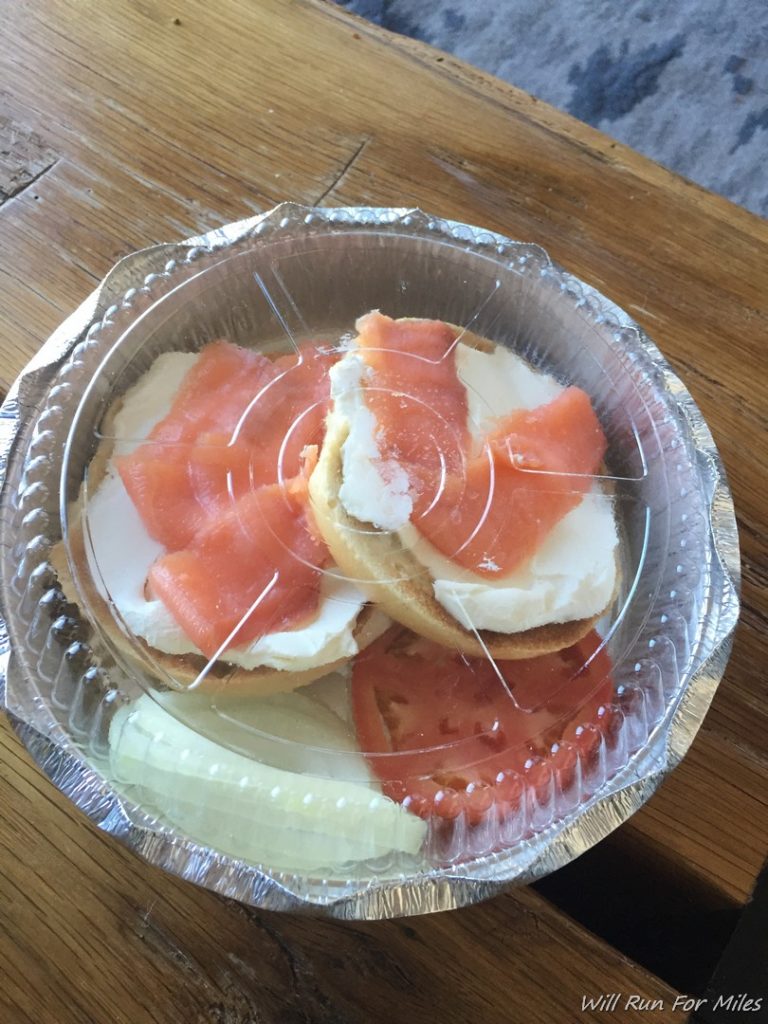 a bagel with cream cheese and salmon in a plastic container