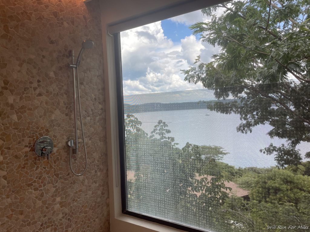 a shower with a view of the water and trees