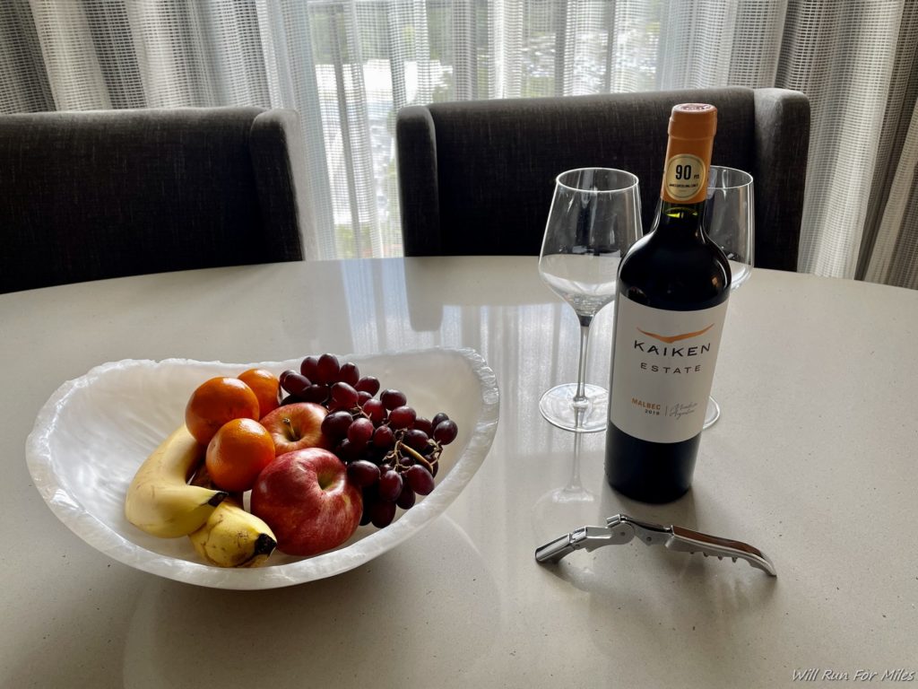a bowl of fruit and a bottle of wine on a table