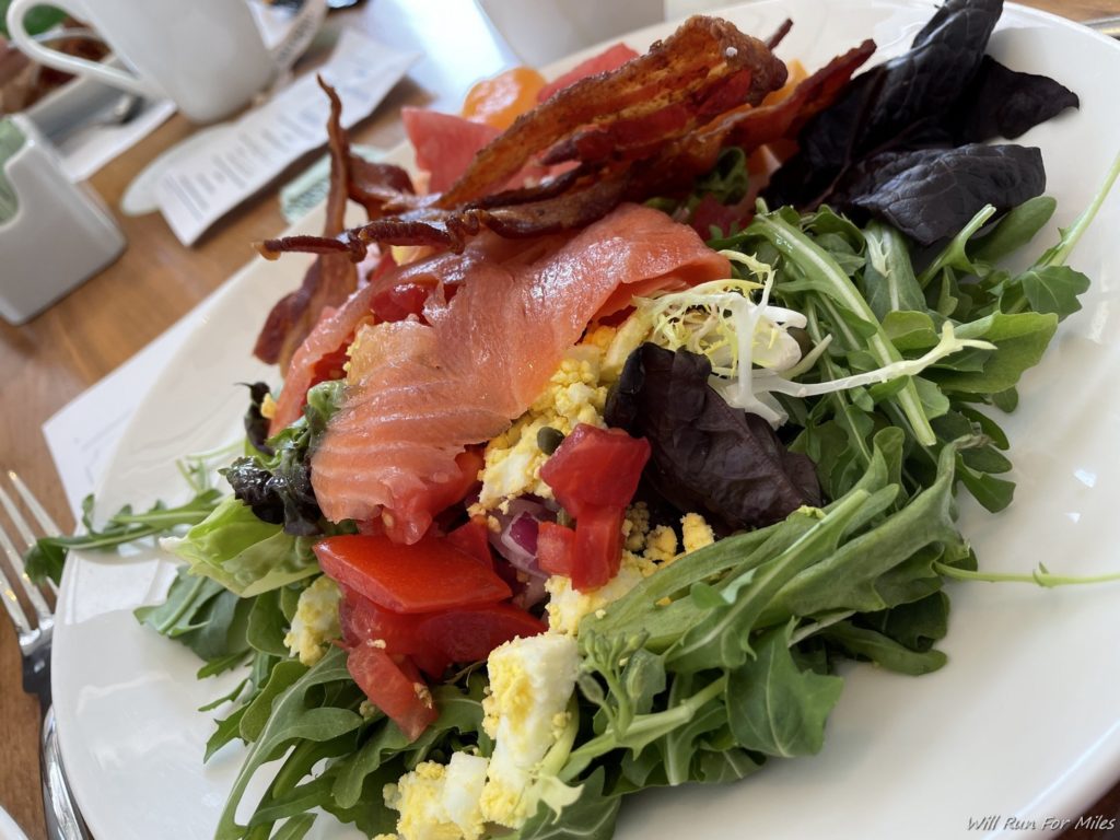 a plate of salad with bacon and vegetables