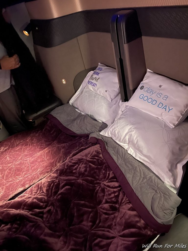 a bed with pillows and a person standing in the back