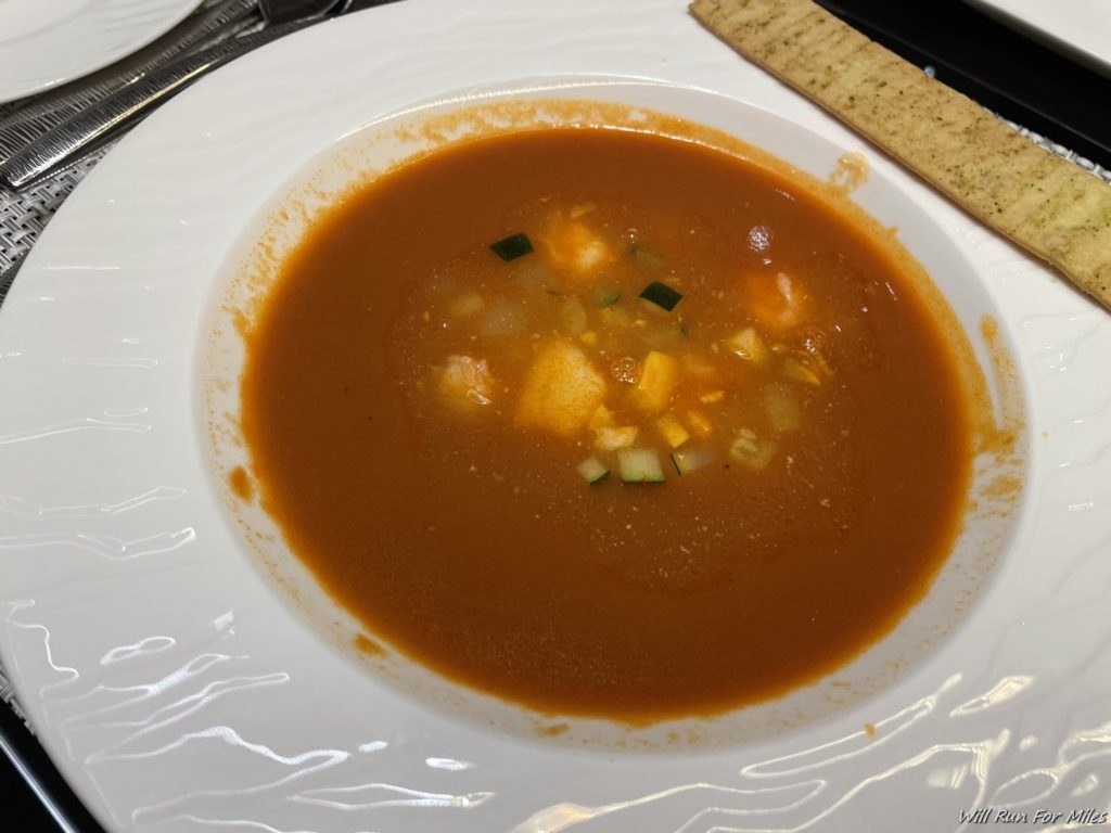 a bowl of soup with a cracker on a plate