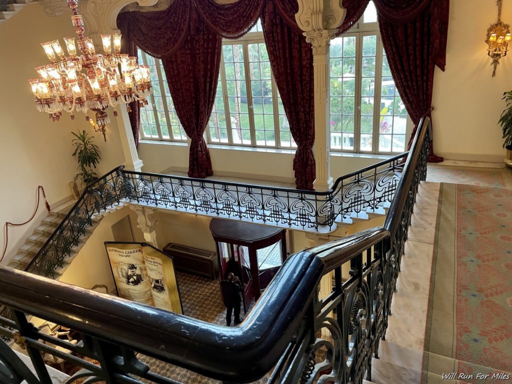 a staircase with a chandelier and a large window
