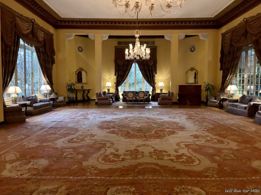 a large room with a large rug and chandelier