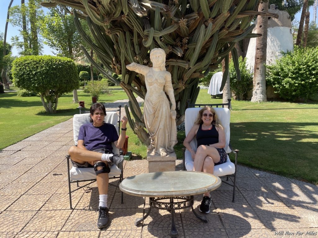 a man and woman sitting in chairs under a statue