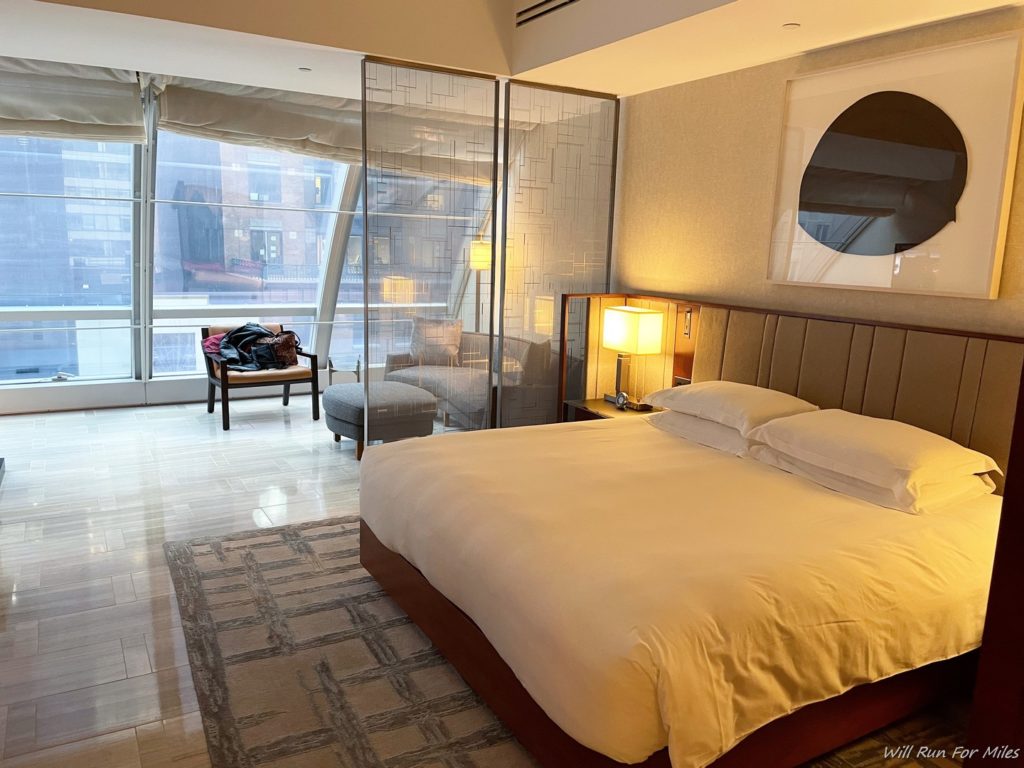 a bedroom with a large bed and a large glass wall