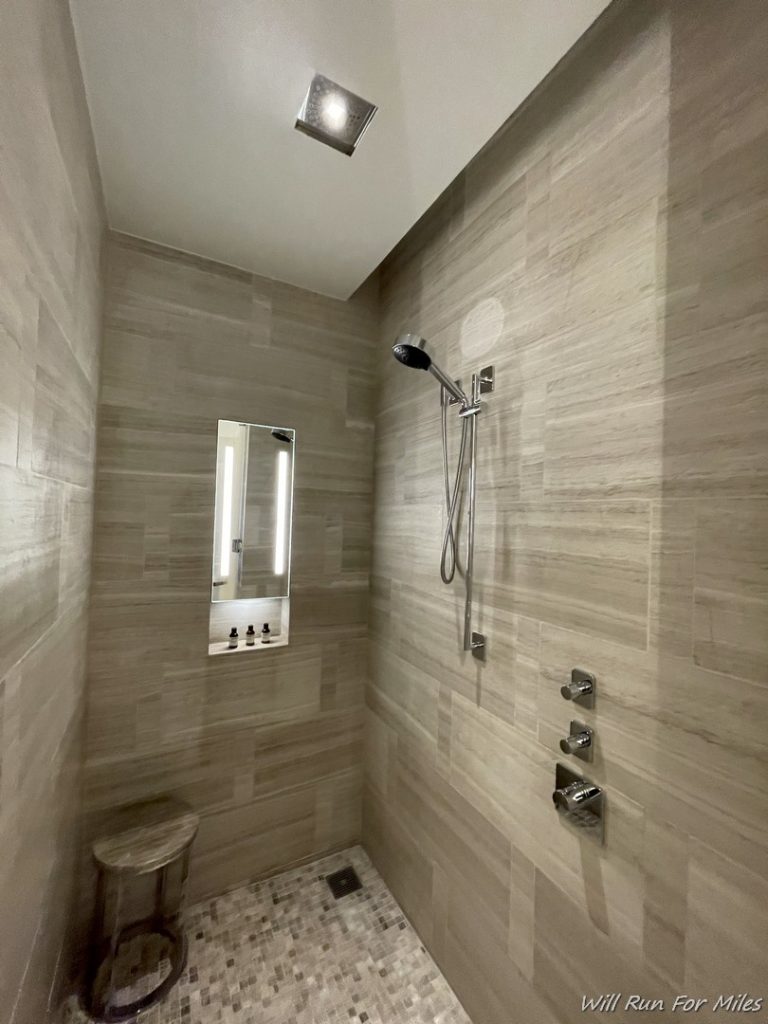 a shower with a mirror and a stool