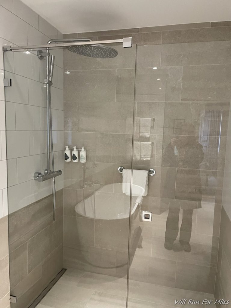 a glass shower with a bathtub and a tub