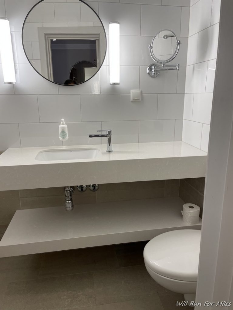 a bathroom with a round mirror and sink