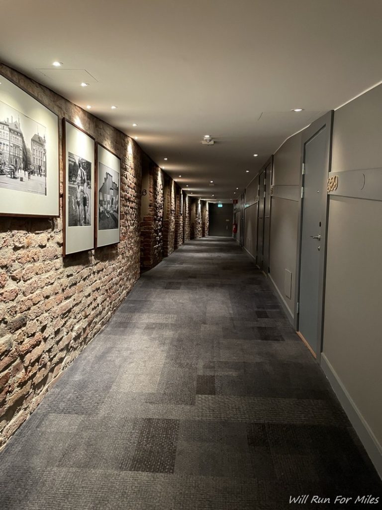 a long brick hallway with pictures on the wall