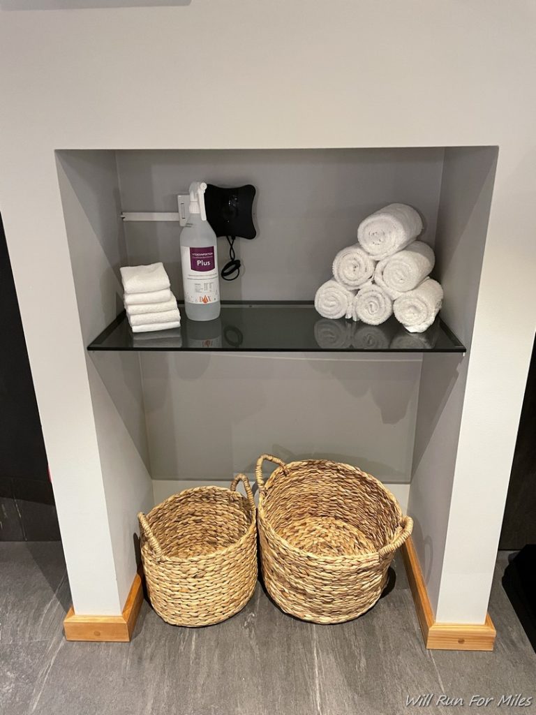 a shelf with towels and a spray bottle
