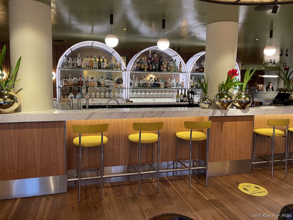 a bar with yellow stools and bottles of liquor