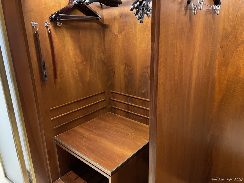 a wooden closet with a bench and swingers