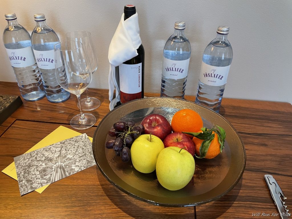 a bowl of fruit and wine bottles on a table