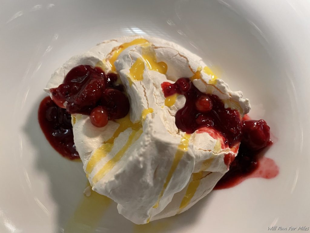 a white dessert with red sauce and fruit on it