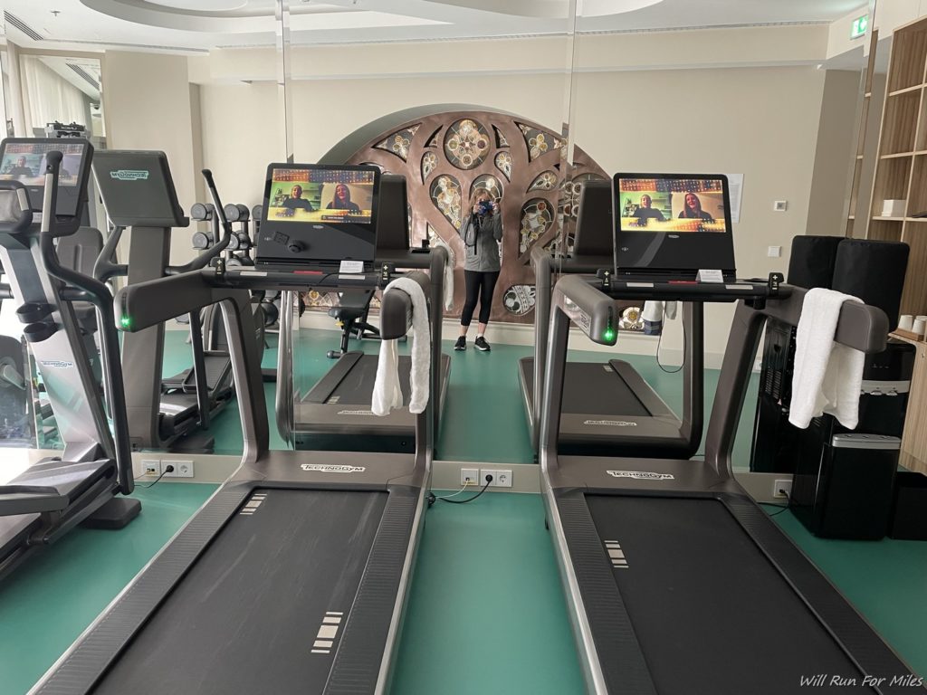 a group of treadmills in a room with a woman standing in the background