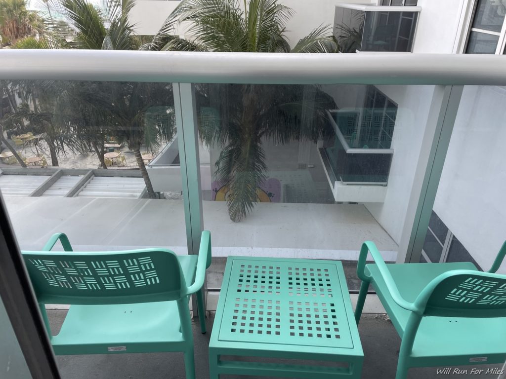 a green chairs and a table outside of a balcony