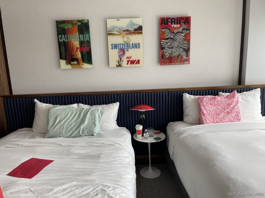 two beds with pillows and posters on the wall