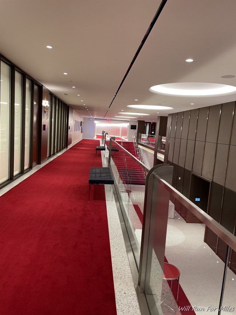 a long hallway with red carpet and glass railings