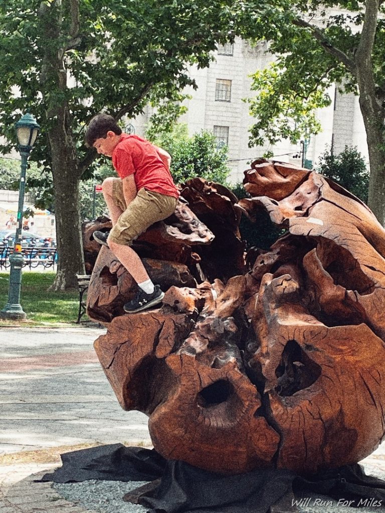 a boy sitting on a large piece of wood
