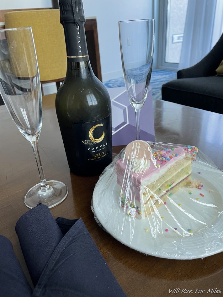 a slice of cake on a plate with two champagne glasses