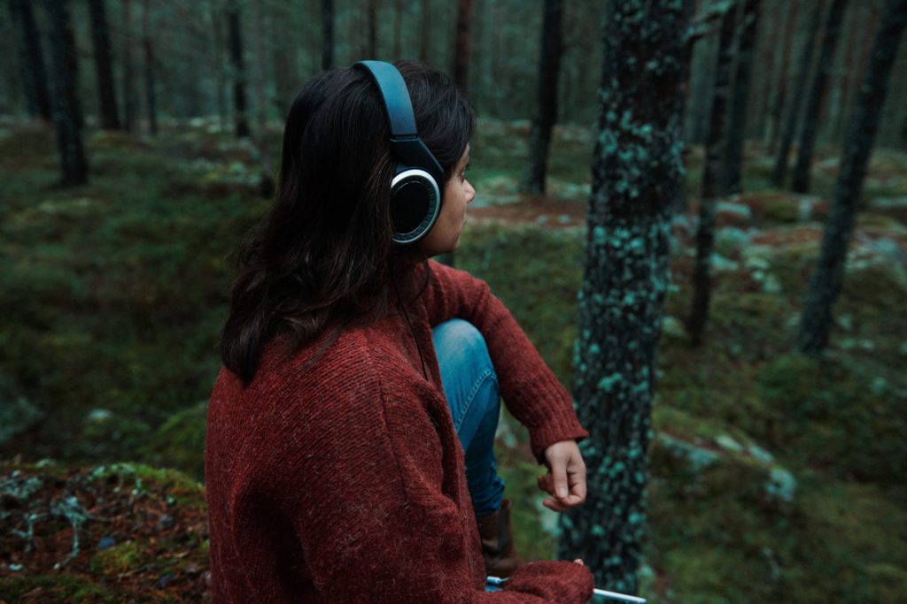 a woman wearing headphones sitting on a rock in the woods