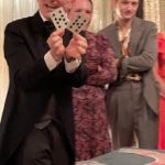 a man in a suit holding up playing cards