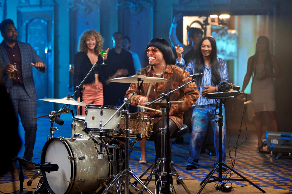 a man playing drums with people in the background