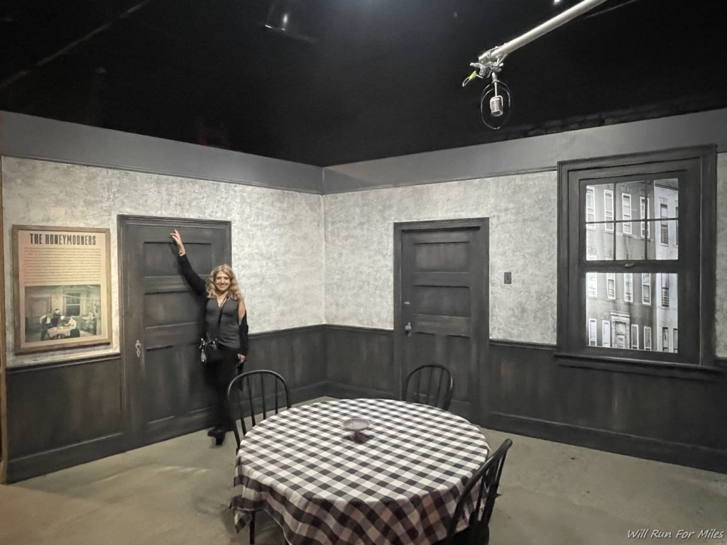 a woman standing in a room with a table and chairs