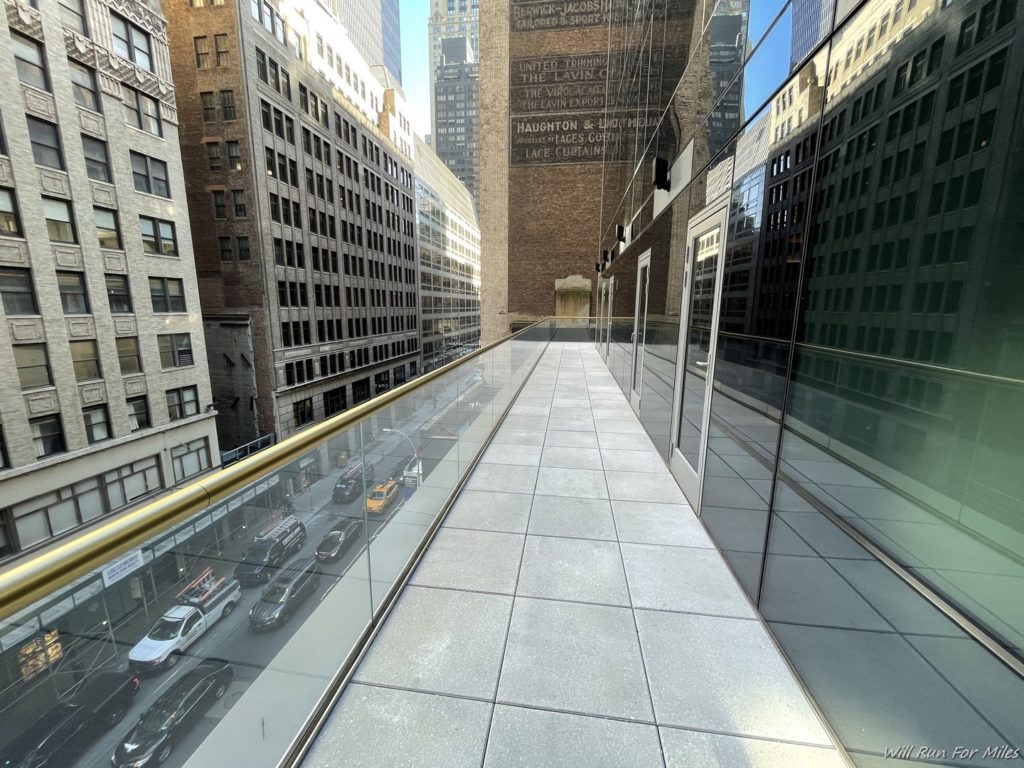 a walkway with a glass railing and a city street