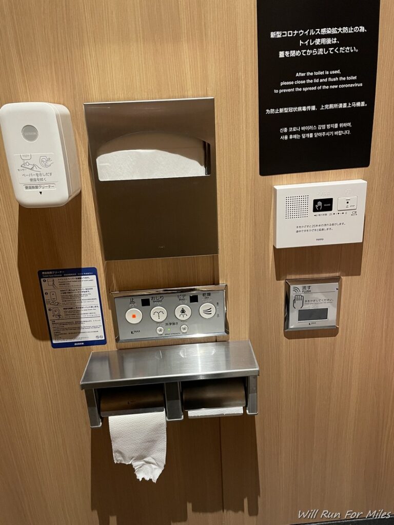 a toilet paper dispenser and a sign on a wall