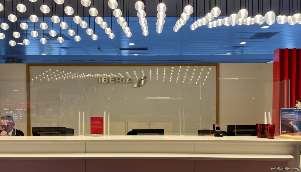 a reception desk with a sign and a group of lights from the ceiling